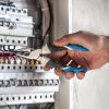 Man, an electrical technician working in a switchboard with fuses. Installation and connection of electrical equipment. Close up.
